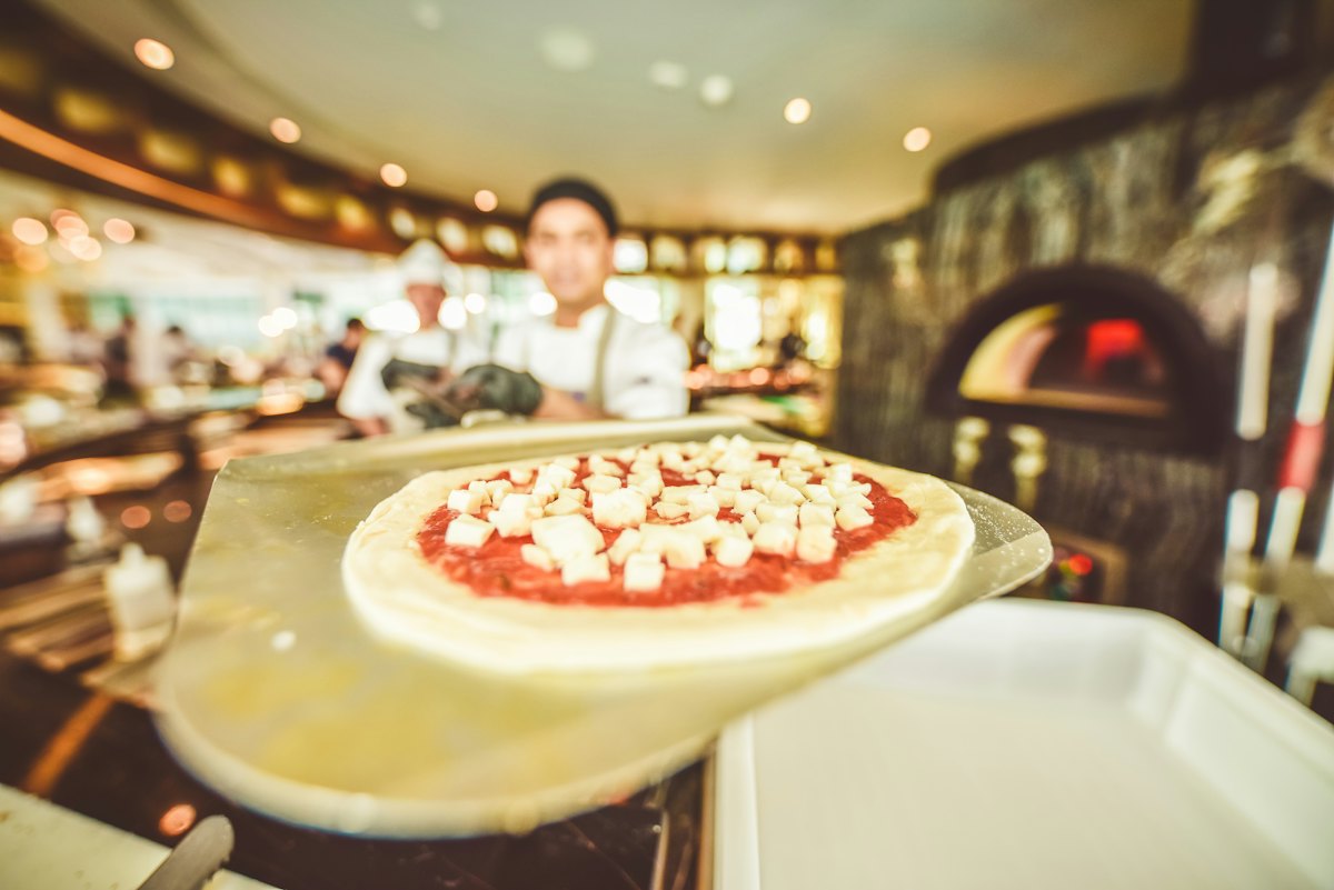 Pizza being finished behind the counter